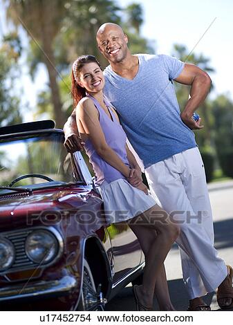 Picture - Smiling couple standing together near classic's car. Fotosearch