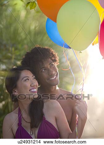 Picture - Smiling couple with balloons. Fotosearch