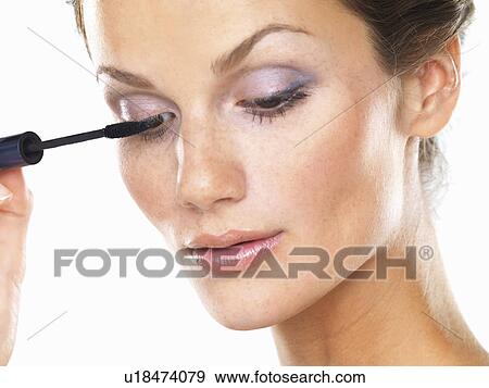 Stock Photo - Studio portrait of beautiful brunette applying mascara. Fotosearch
