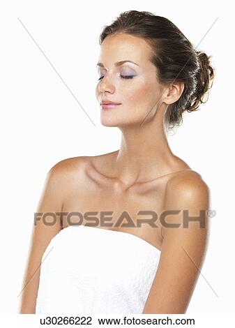 Stock Image - Studio portrait of beautiful woman wrapped in towel with eyes closed. Fotosearch