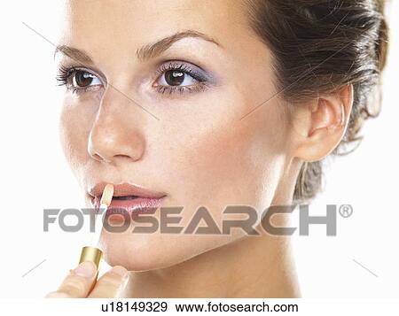 Stock Photo - Studio portrait of beautiful woman applying lip gloss. Fotosearch