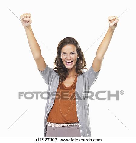 Stock Image - Studio portrait of woman enjoying success with hands raised. Fotosearch