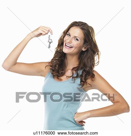 Stock Image - Studio portrait of woman holding keys and smiling. Fotosearch