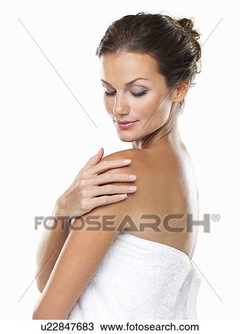 Stock Image - Studio portrait of young attractive woman wrapped in towel with hand on shoulder. Fotosearch