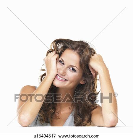 Stock Photo - Studio portrait of young woman sitting at table and smiling. Fotosearch