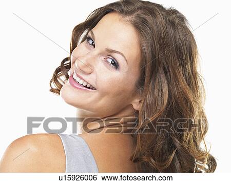 Studio portrait of young woman smiling and looking over shoulder View Large Photo Image Stock Photograph - Studio portrait of young woman smiling and looking over shoulder. Fotosearch