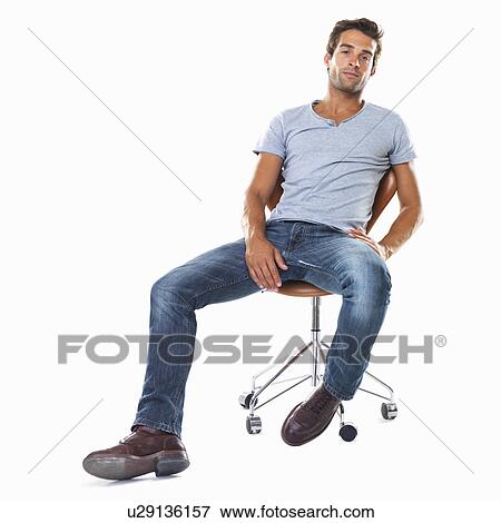 Stock Photo - Studio shot of handsome young man sitting comfortably on chair. Fotosearch