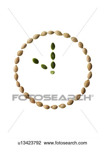 Stock Image - Studio shot of Pumpkin Seeds in shape of clock on white background. Fotosearch