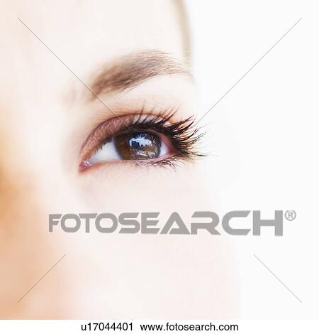 Stock Image - Studio shot of young woman, close-up of eye. Fotosearch