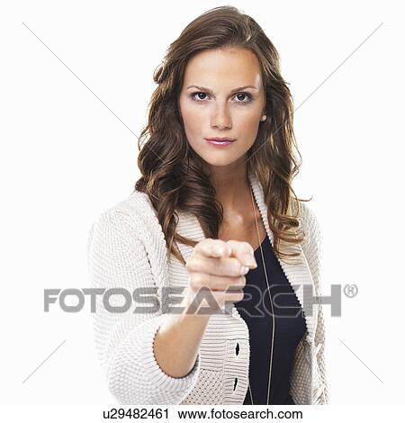 Stock Image - Studio shot of young woman pointing at camera. Fotosearch