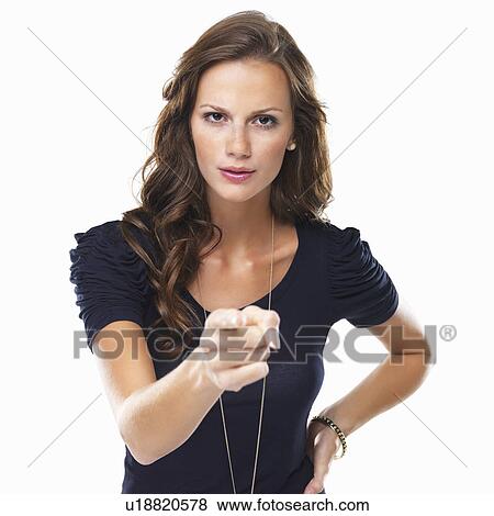 Stock Photo - Studio shot of young woman pointing at camera. Fotosearch