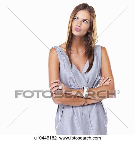 Stock Image - Thoughtful woman standing with hands folded and pursing her lips. Fotosearch