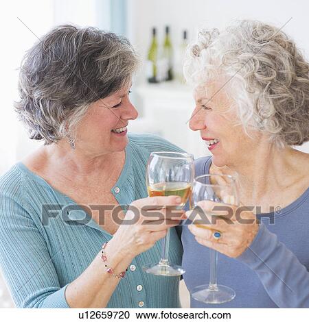 Two senior women holding wine glasses View Large Photo Image Stock Image - Two senior women holding wine glasses. Fotosearch