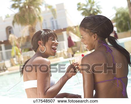 Stock Photo - USA, Arizona, Scottsdale, Two females enjoying drink by pool. Fotosearch