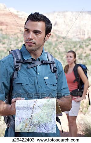Stock Image - USA, Arizona, Sedona, Young couple hiking, man holding map. Fotosearch