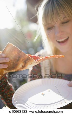 Stock Image - USA, Brooklyn, Williamsburg, Woman eating pizza. Fotosearch