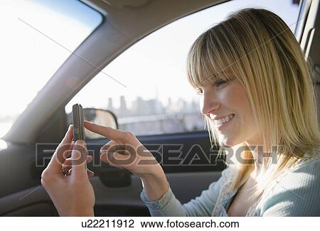 Stock Image - USA, Brooklyn, Williamsburg, Woman using smart phone in car. Fotosearch