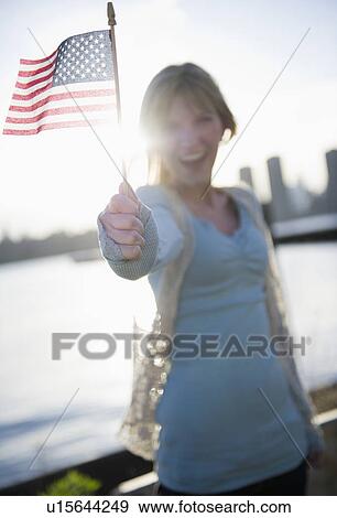Stock Photo - USA, Brooklyn, Williamsburg, Woman holding American flag. Fotosearch