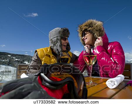 Stock Image - USA, Colorado, Telluride, Couple enjoying outdoor meal at ski resort. Fotosearch