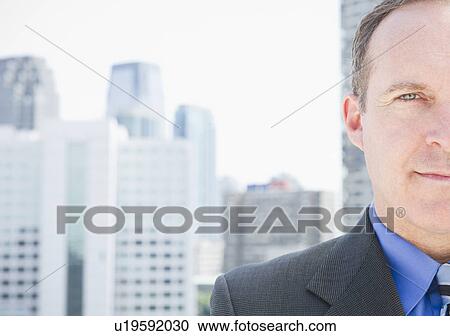 Stock Image - USA, New Jersey, Jersey City, Portrait of businessman against cityscape. Fotosearch