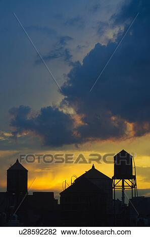 Stock Image - USA, New York City, silhouettes of buildings at sunset. Fotosearch