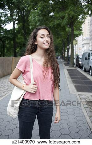 Stock Image - USA, New York, New York City, Portrait of smiling young woman standing on street. Fotosearch