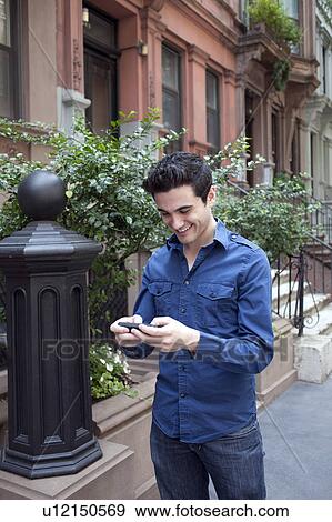 USA, New York, New York City, Young man texting on street View Large Photo Image Stock Photo - USA, New York, New York City, Young man texting on street. Fotosearch