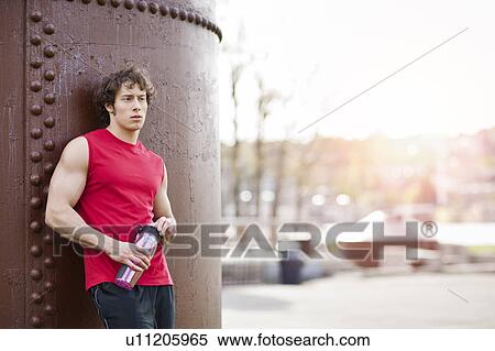 Stock Photography - USA, Washington State, Seattle, Young athlete leaning against building. Fotosearch