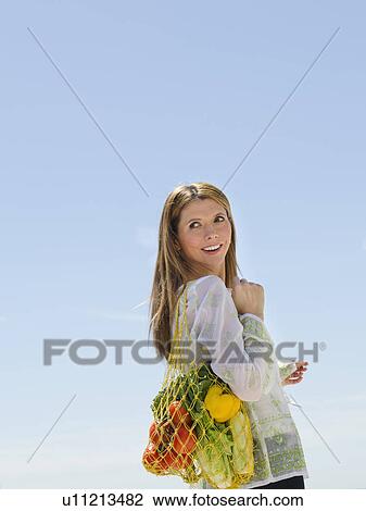 Woman carrying net bag of fruit and vegetables outdoors View Large Photo Image Stock Image - Woman carrying net bag of fruit and vegetables outdoors. Fotosearch