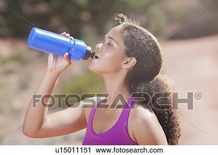 Stock Image - Woman drinking water after jogging. Fotosearch