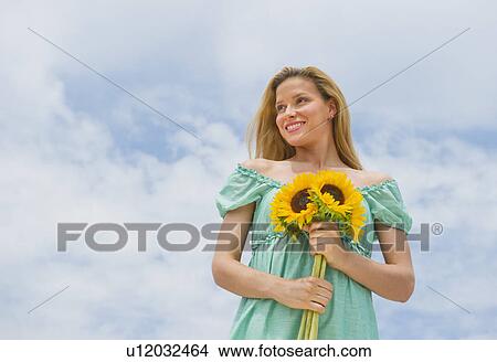 Picture - Woman holding sunflowers. Fotosearch
