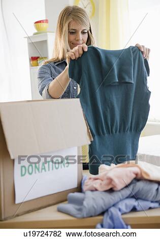 Woman preparing clothes for donation View Large Photo Image Stock Image - Woman preparing clothes for donation. Fotosearch