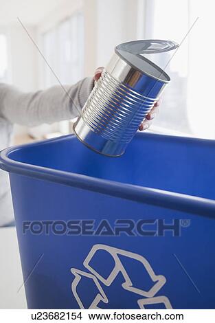 Woman putting metal can into blue recycling bin View Large Photo Image Picture - Woman putting metal can into blue recycling bin. Fotosearch