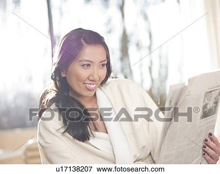 Stock Photo - Woman reading newspaper in hotel. Fotosearch
