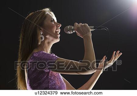 Stock Photo -  Woman singing in spotlight. Fotosearch