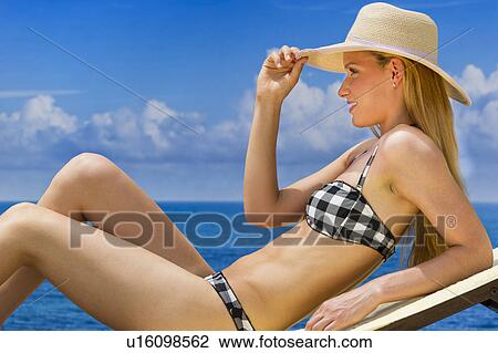 Stock Image - Woman sunbathing by sea. Fotosearch