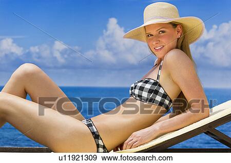 Stock Photo - Woman sunbathing by sea. Fotosearch