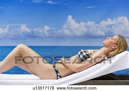 Stock Photo - Woman sunbathing by sea. Fotosearch
