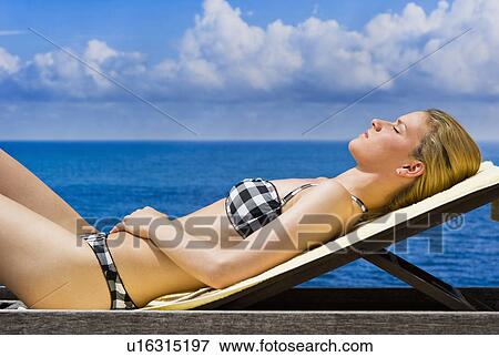 Stock Photo - Woman sunbathing by sea. Fotosearch