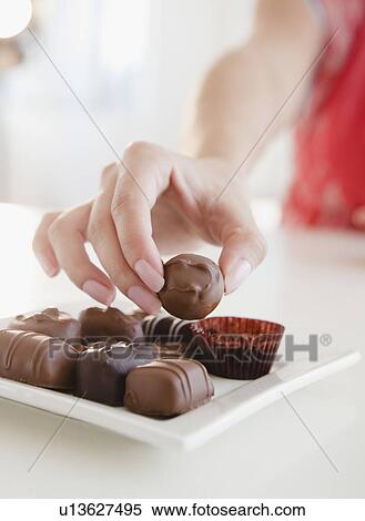 Stock Photography - Woman taking praline. Fotosearch