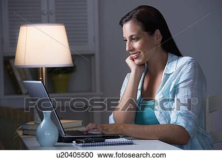 Woman using laptop at night View Large Photo Image Stock Image - Woman using laptop at night. Fotosearch