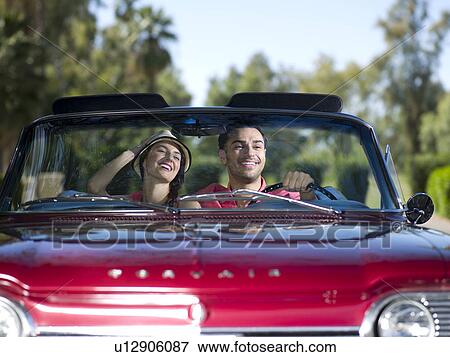 Stock Photo - Young couple driving convertible car. Fotosearch