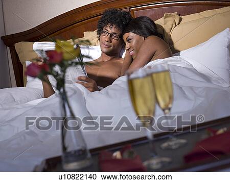 Young couple lying together in bed View Large Photo Image Stock Image - Young couple lying together in bed. Fotosearch