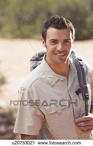 Stock Image - Young man hiking in desert. Fotosearch