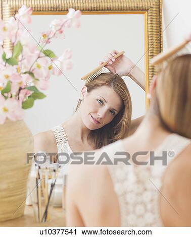 Young woman brushing hair in front of mirror View Large Photo Image Stock Image - Young woman brushing hair in front of mirror. Fotosearch