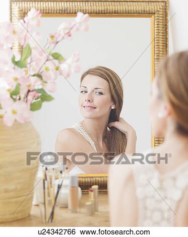 Young woman brushing hair in front of mirror View Large Photo Image Stock Photograph - Young woman brushing hair in front of mirror. Fotosearch