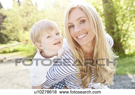Young woman giving piggyback ride to son (2-3) in park View Large Photo Image Stock Photo - Young woman giving piggyback ride to son (2-3) in park. Fotosearch
