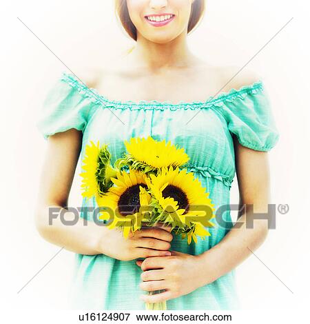 Stock Photo - Young woman holding sunflowers. Fotosearch