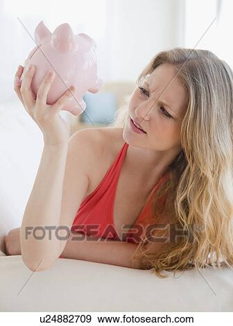 Young woman looking at piggybank View Large Photo Image Stock Photo - Young woman looking at piggybank. Fotosearch