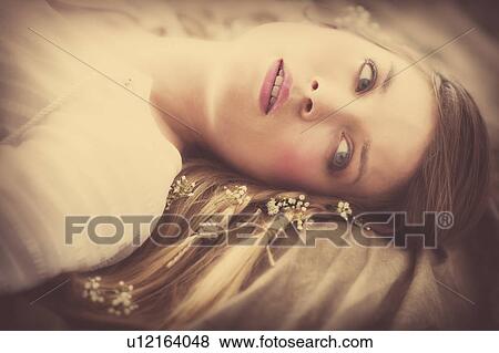 Stock Photo - Young woman lying with flowers in hair. Fotosearch